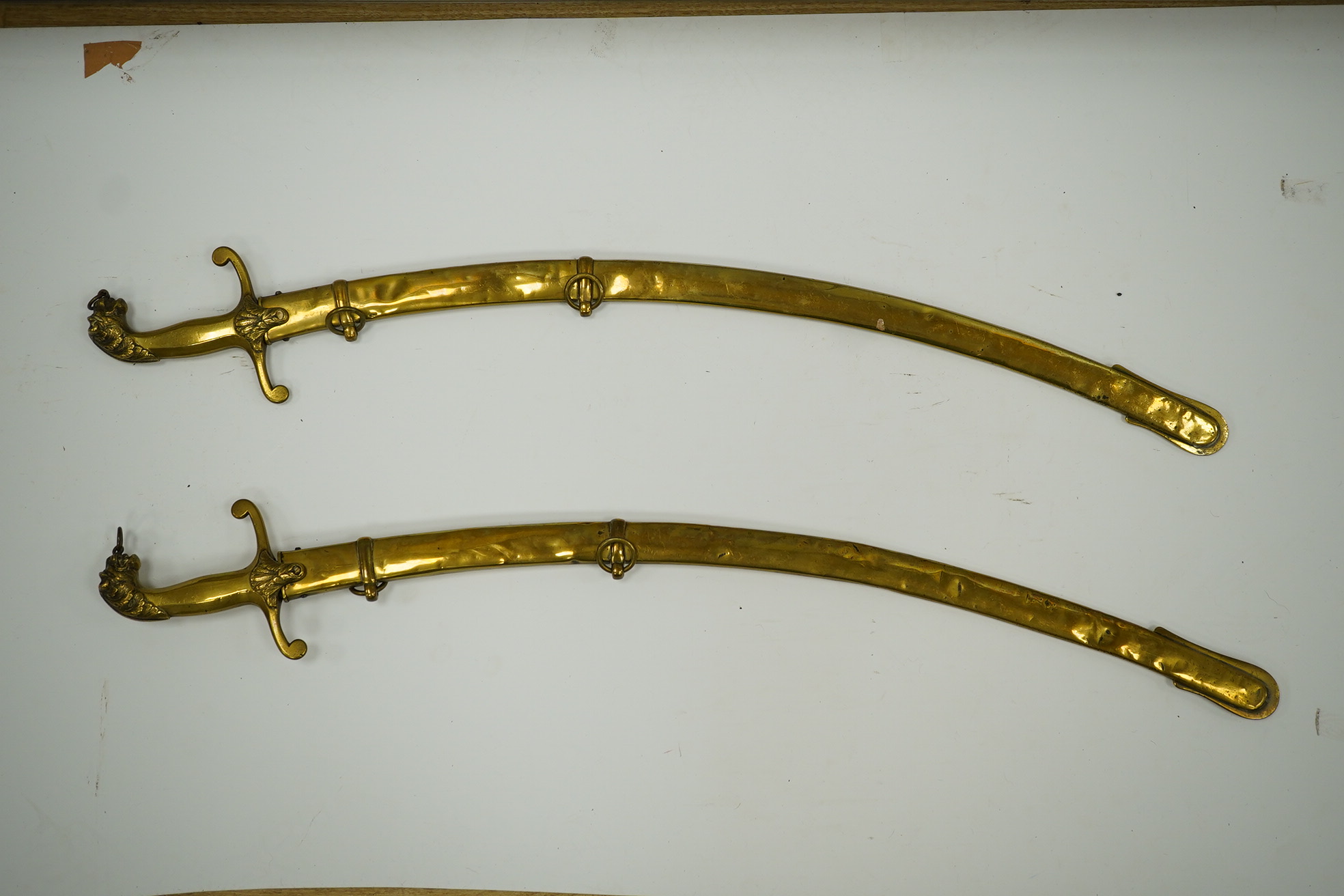 A pair of Victorian bandsman’s swords of Shamshir type, curved single edge blades, cast brass hilts with lions head pommels, in their brass scabbards. Condition - good, some dents to scabbards.